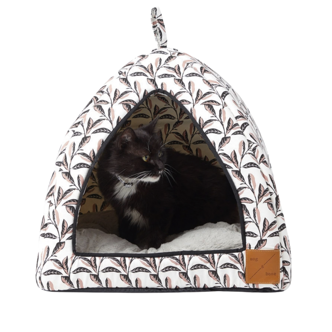 Pet bed with a pink leaf pattern and a cat inside on a white background