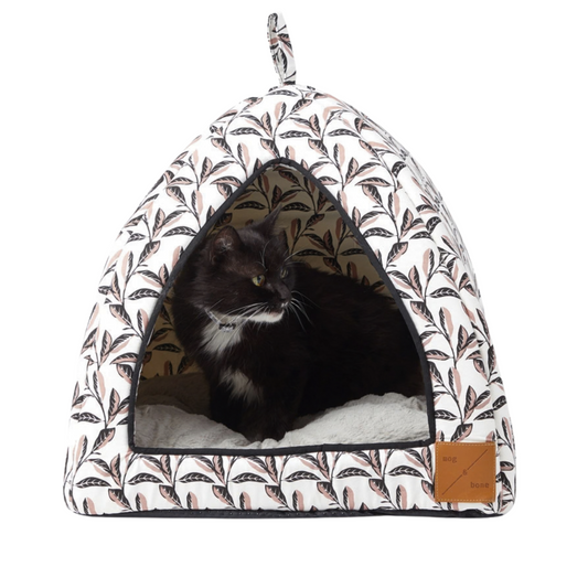 Pet bed with a pink leaf pattern and a cat inside on a white background