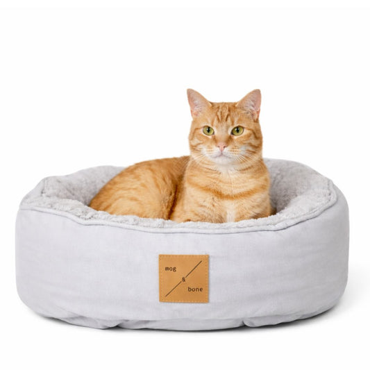 Cat sitting in a gray pet bed with 'mog & bone' label on a white background