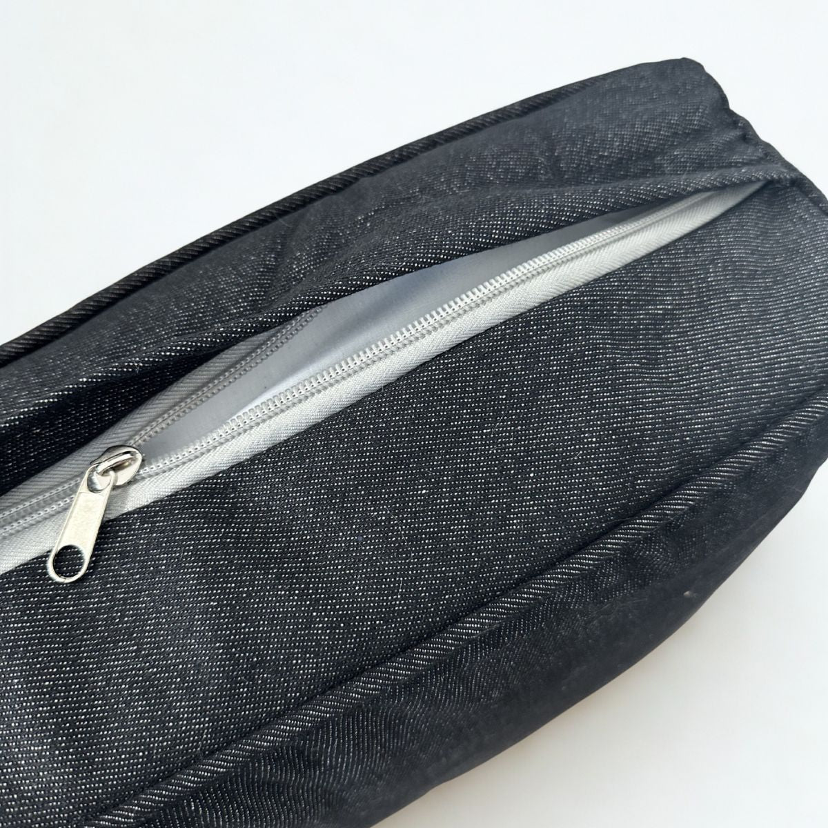Black denim dog bed with a silver zipper on a white background