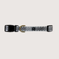A black dog collar with a wave print design and brass fittings, displayed against a white background.
