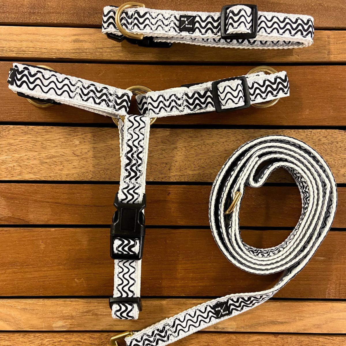 Dog collar and leash set with black and white wave pattern on a wooden surface