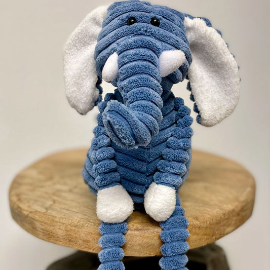 Blue plush elephant toy on a wooden stool with a plain background