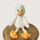 White plush duck with orange feet and beak on a wooden surface