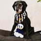 Dog wearing a navy Hampton stripe bandana with a toy on a cushion bed
