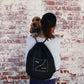 Person holding a dog and a black drawstring bag with 'mag & bone' logo against a brick wall.