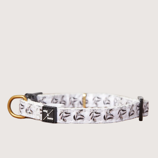 Adjustable hemp cat collar with a shadow quartz print and brass bell fitting, displayed on a wooden surface.