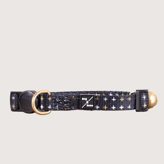 Adjustable black neoprene cat collar with metallic cross print and a brass bell fitting.